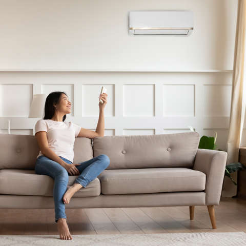 a woman staying cool in the summer with an energy-efficient air conditioner.
