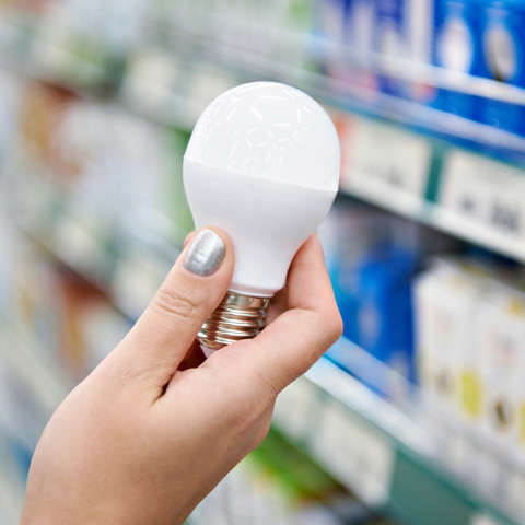 Person choosing to switch to energy-efficient LED light bulbs